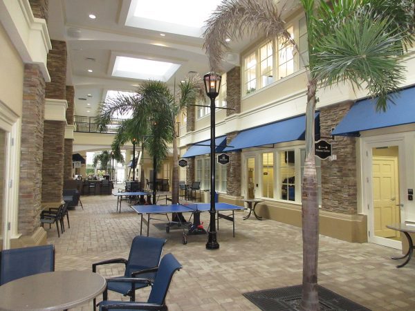 corridor of palm trees and ping pong tables and hightop tables