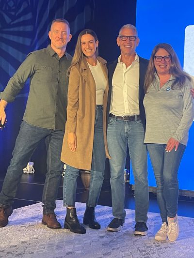 4 employees posing for a picture together on a stage