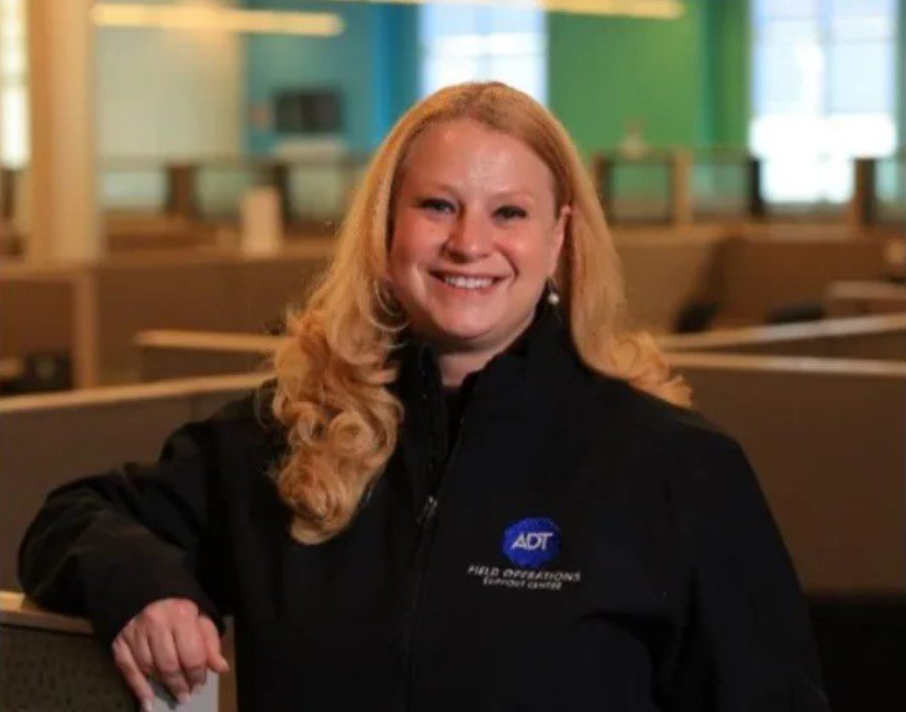 amy standing in front of cubicles in an office with a black ADT quarter zip on